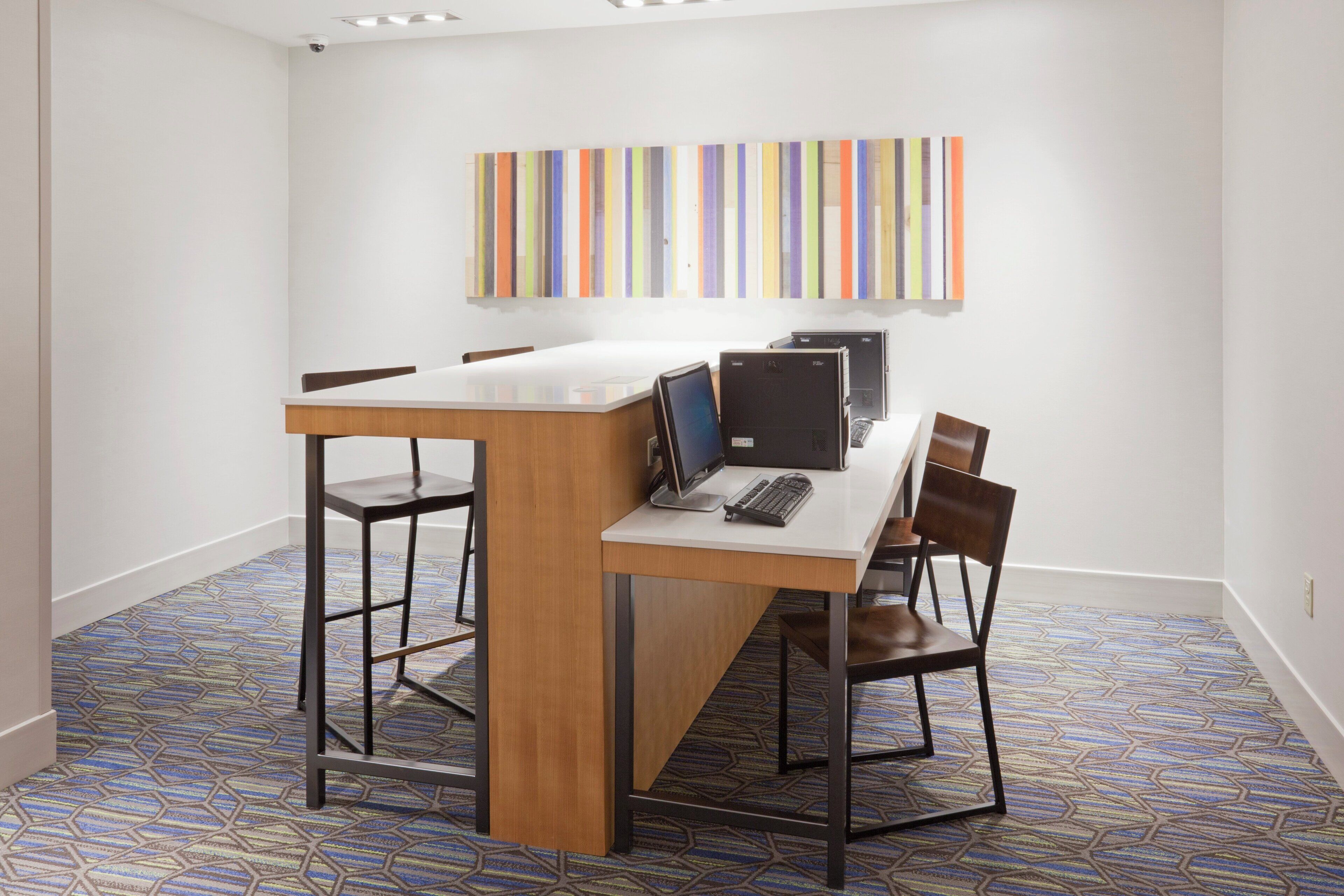 A conference room with a long table, two chairs, a computer, and a monitor.