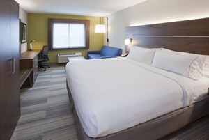 Habitación de hotel con una cama grande, un escritorio, una silla y un ventanal.