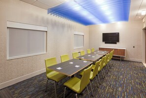 A conference room with a long table, yellow chairs, a flat-screen TV, and a patterned carpet. - Holiday Inn Express Roseville-St. Paul by IHG (Roseville)