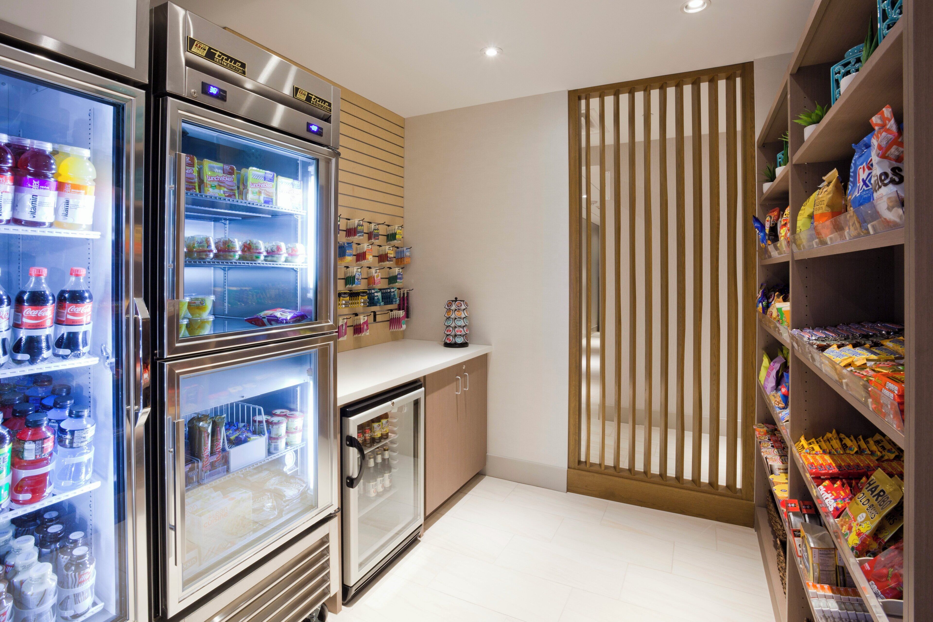 A well-lit kitchen with stainless steel appliances, including a refrigerator and a mini-fridge, stocked with beverages and snacks.