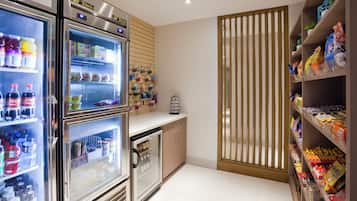 A well-lit kitchen with stainless steel appliances, including a refrigerator and a mini-fridge, stocked with beverages and snacks.