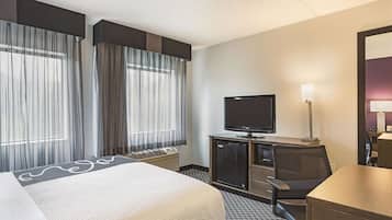 Una habitación de hotel con una cama, televisor, escritorio y silla.