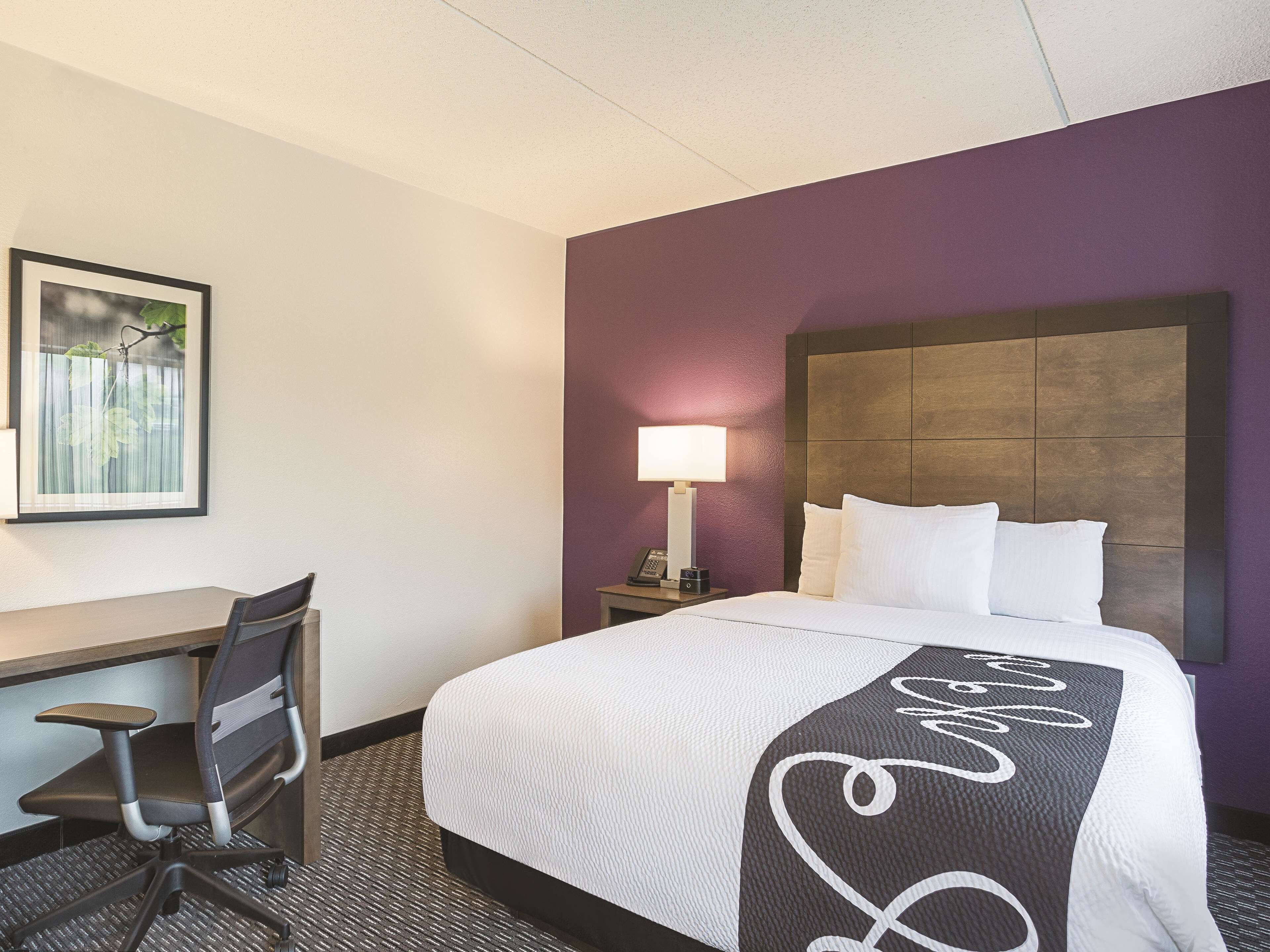 A hotel room with a bed, a desk, and a chair.