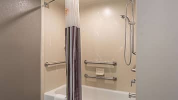A modern bathroom with a bathtub, shower, and grab bars.