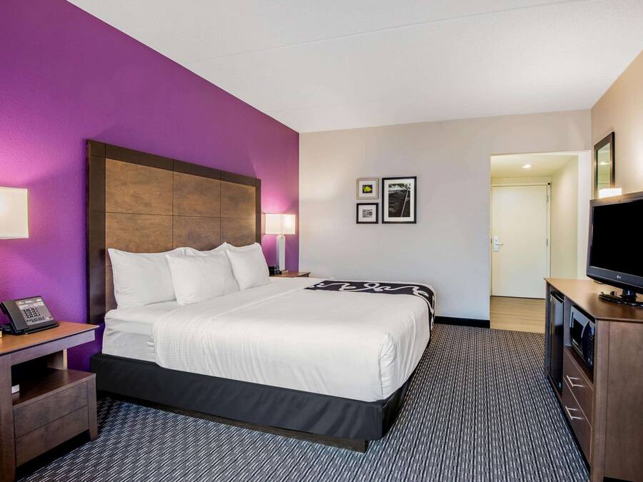 Hotelkamer met een groot bed, een bureau met telefoon, een televisietoestel en een tv aan de muur.