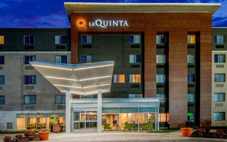 A hotel with a modern design, featuring a prominent 'La Quinta' sign, a covered entrance, and a well-lit facade.