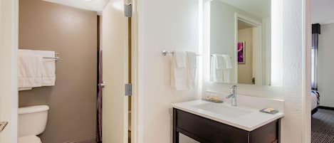A bathroom with a white sink, a mirror, and a toilet.
