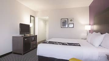 Ein Hotelzimmer mit einem Bett, einem Fernseher auf einer Kommode, einer Mikrowelle und einer Tür zu einem anderen Raum.