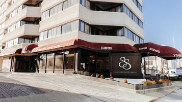 Stamford Suites Hotel features a modern architectural design with a prominent corner entrance and accessible stairs leading up to the main door.