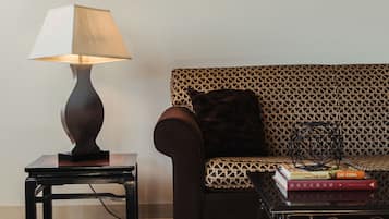 A room with a sofa, a table with a lamp, and two framed pictures on the wall.