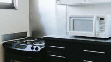 Una cucina con piano cottura, forno a microonde e pensili neri.