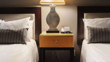 Habitación de hotel con dos camas, una mesita de noche con lámpara, teléfono y espejo en la pared.