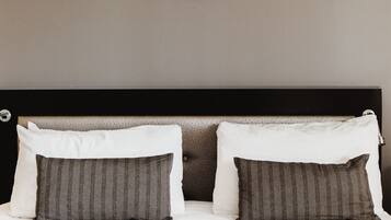 A neatly made bed with two pillows, a headboard, and a circular wall decoration above it.