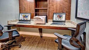 A conference room with two desktop computers, a printer, and two office chairs.