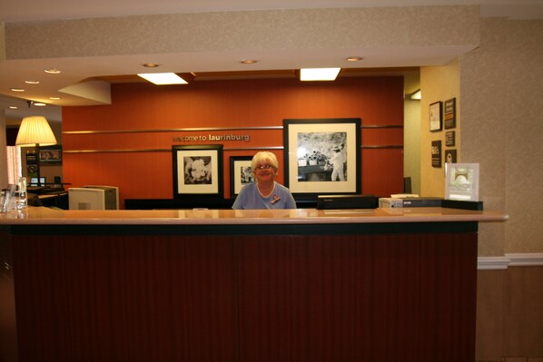 A reception desk with framed photographs on the wall and a sign that reads "Welcome to Laurinburg."