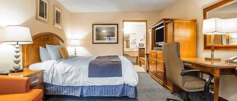 A hotel room with a bed, desk, chair, dresser, and a television.
