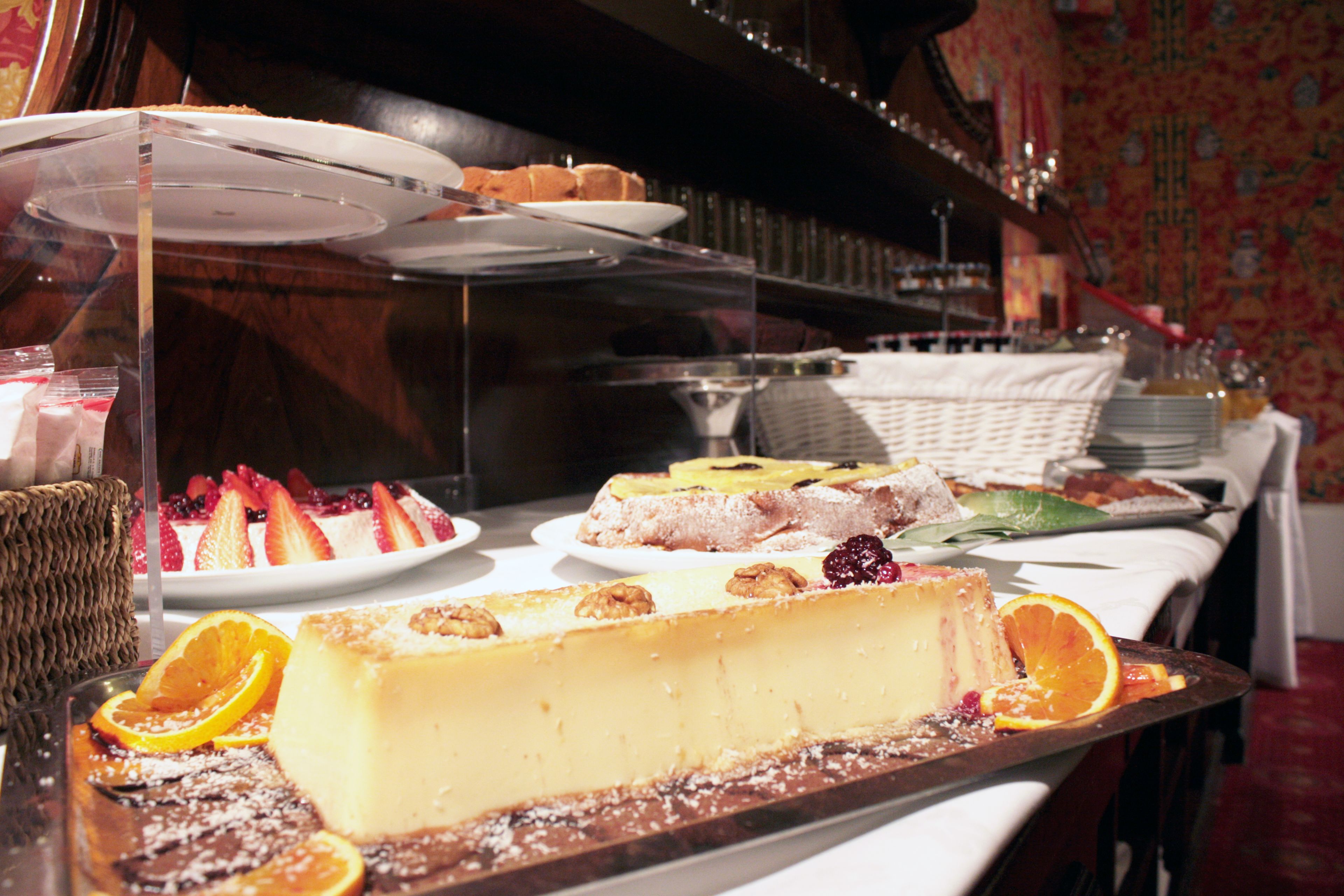 Et dessertbord med forskellige kager og bagværk, herunder en cheesecake og en frugttærte.