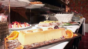 A dessert display with various cakes and pastries, including a cheesecake and a fruit tart.