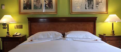Habitación de hotel con una cama grande, dos mesitas de noche, un cabecero de madera y dos obras de arte enmarcadas en la pared.