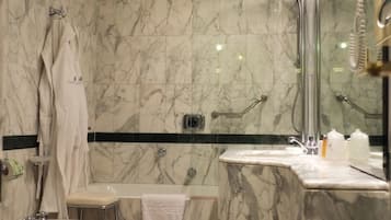 A bathroom with marble walls, a bidet, a toilet, a sink, and a shower.