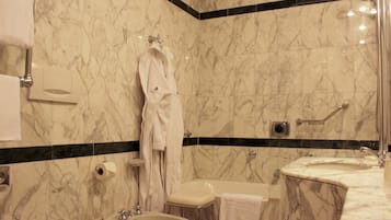 Une salle de bain avec un mur en marbre, une baignoire, un lavabo et un bidet.