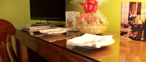 A reception desk with a basket of gifts, a television, and a framed picture on the wall.
