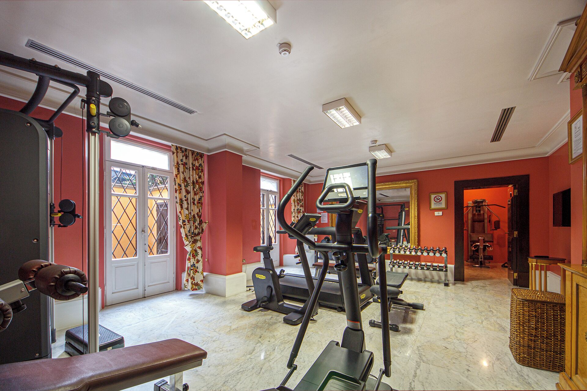 A gym with various exercise equipment, a bench, and a mirror.