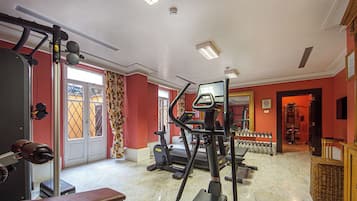 A gym with various exercise equipment, a bench, and a mirror.