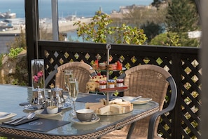 Enjoy a meal on the balcony with a view of the sea, surrounded by wicker chairs and a beautifully set table.