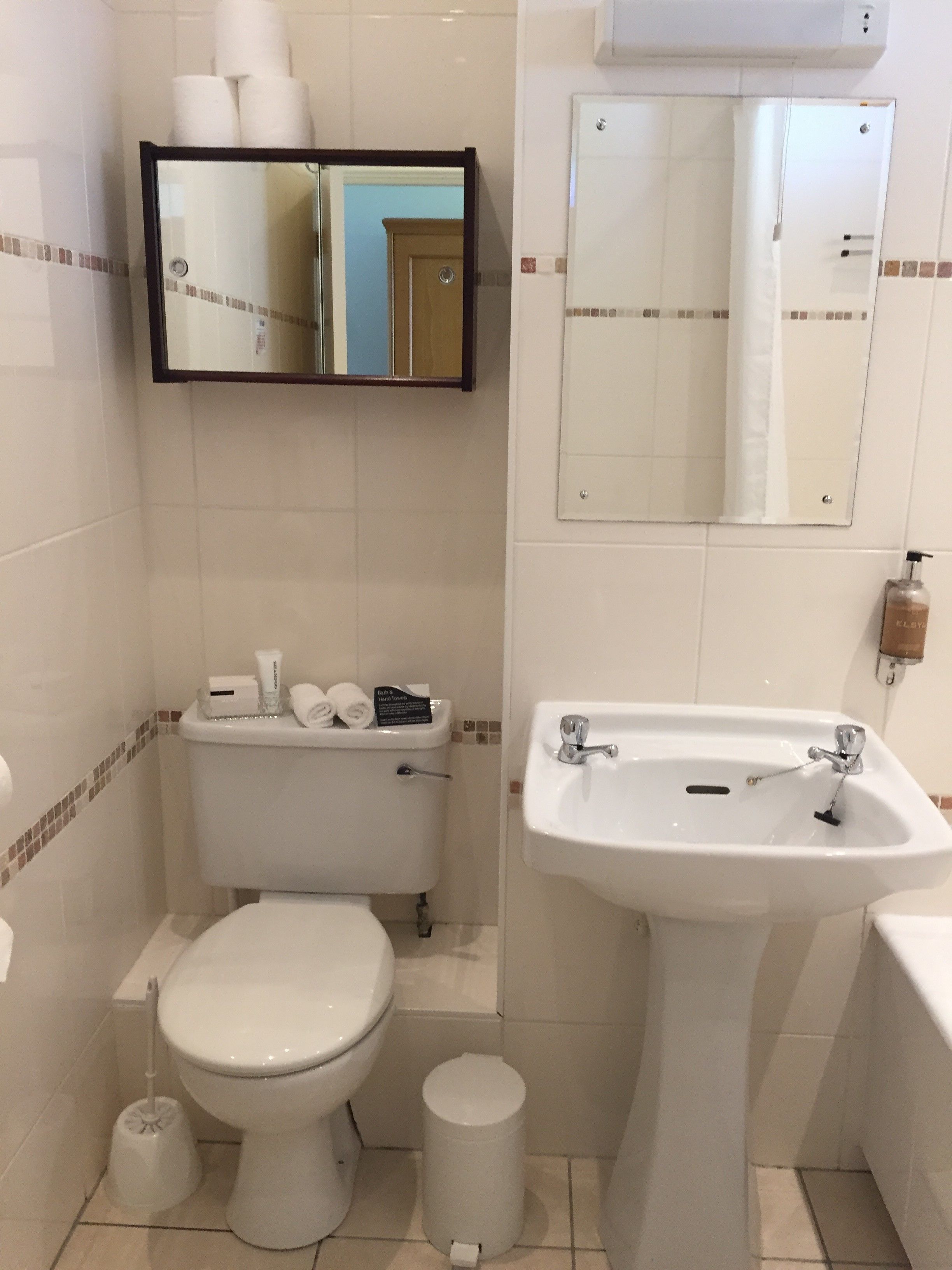 A bathroom with a toilet, bidet, sink, and a mirror.