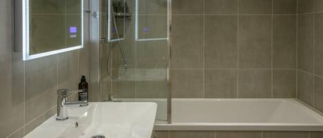Baño con lavamanos, espejo y cabina de ducha.