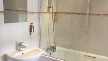Un bagno moderno con doccia vetro, lavabo su piedistallo e un ampio specchio.