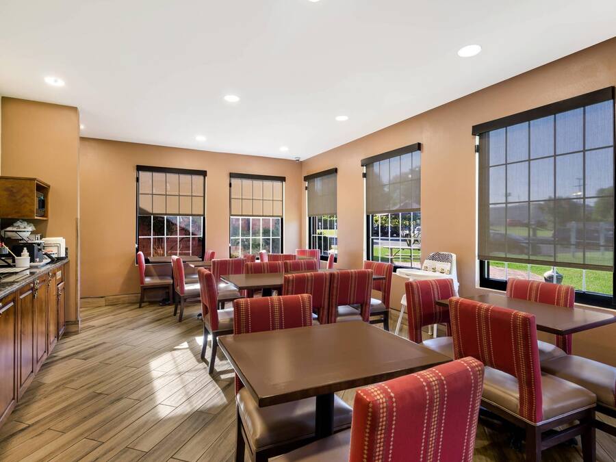 Un restaurante con piso de madera, asientos tapizados en rojo y ventanas amplias con vistas al exterior.