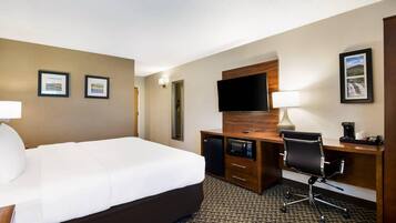 A hotel room with a large bed, a desk with a computer, a television, and a coffee maker.