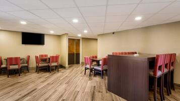 A conference room with a large table and chairs, a flat-screen TV, and a wooden floor.