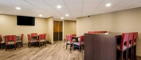 A conference room with a large table and chairs, a flat-screen TV, and a wooden floor.