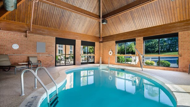 An indoor swimming pool with a wooden ceiling and brick walls, surrounded by lounge chairs and large windows. - Comfort Inn Lexington Virginia Horse Center (Lexington)