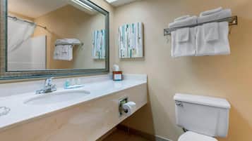 A bathroom with a sink, mirror, towel rack, toilet, and two abstract paintings on the wall.