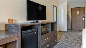 Habitación de hotel con televisión de pantalla plana, microondas, mini refrigerador y escritorio de madera.