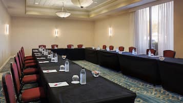 A conference room with a long table, red chairs, and a carpeted floor.