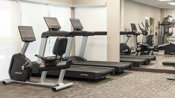 A gym with treadmills, elliptical machines, and weight equipment.