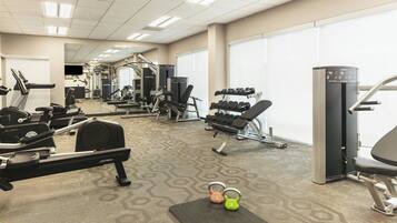Et fitnesscenter med løbebånd, styrketræningsudstyr og håndvægte.