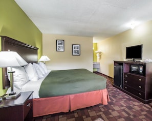 A hotel room with a bed, bedside lamps, a television, a microwave, and a dresser. - Econo Lodge Biltmore (Asheville)