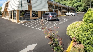 Ein Motel mit Parkplatz, ein Gebäude mit Satteldach und einem wolkenlosen Himmel.