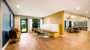 A modern hotel lobby with wooden flooring, a reception desk, and a seating area with chairs and a bench. - Sonesta Select Philadelphia Airport (Philadelphia)