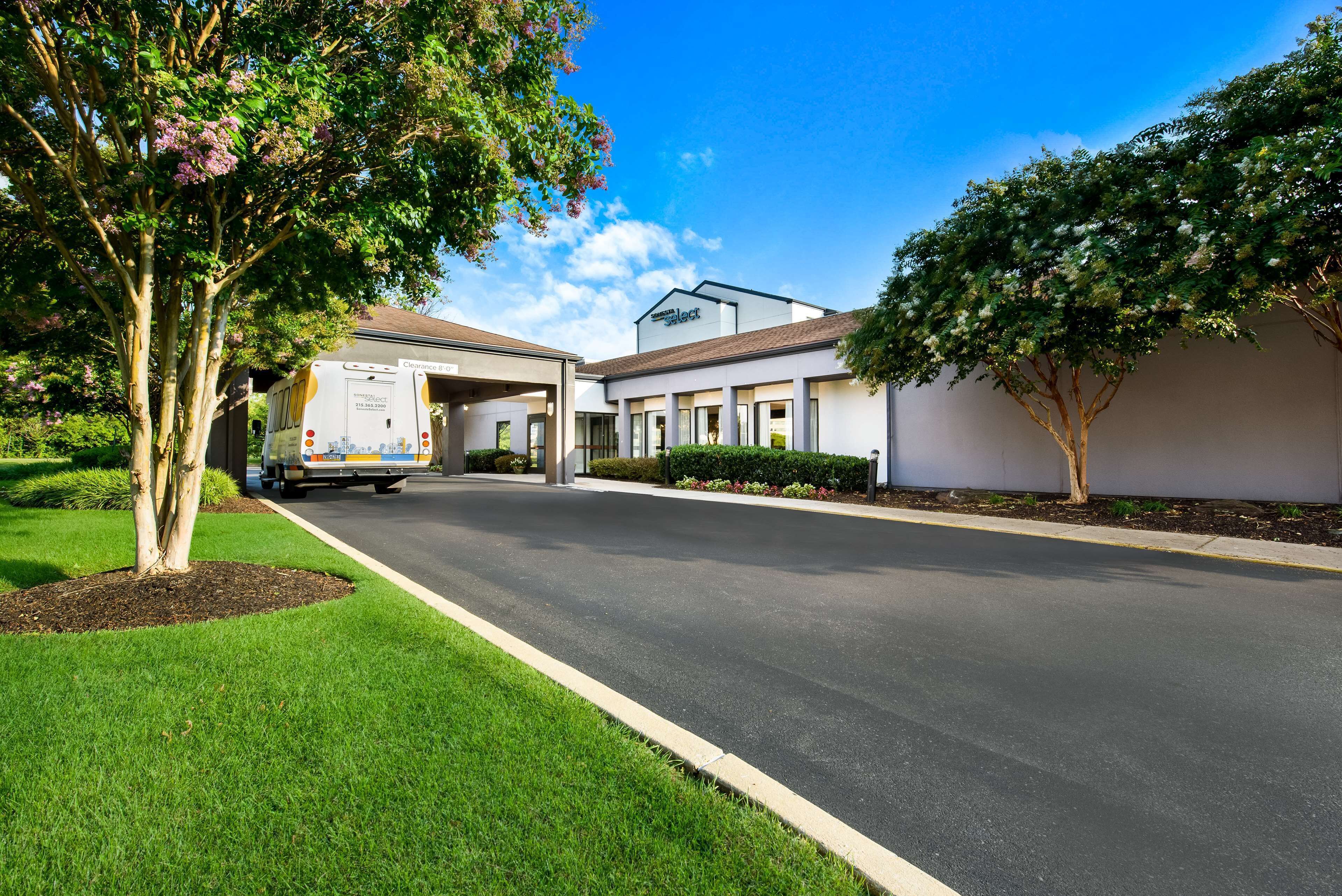 A modern building with a covered entrance, a well-maintained lawn, and a clear sky.