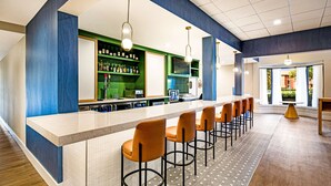 A bar area with a counter, bar stools, and a green shelf with bottles. - Sonesta Select Philadelphia Airport (Philadelphia)