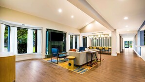 A spacious living area with a large TV, a sofa, and a dining table. - Sonesta Select Philadelphia Airport (Philadelphia)