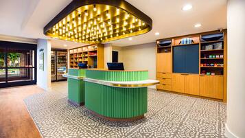 A reception area with a green counter, a patterned floor, and a ceiling with recessed lighting.