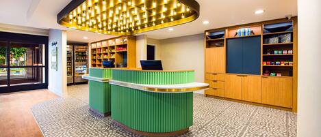 A reception area with a green counter, a patterned floor, and a ceiling with recessed lighting.